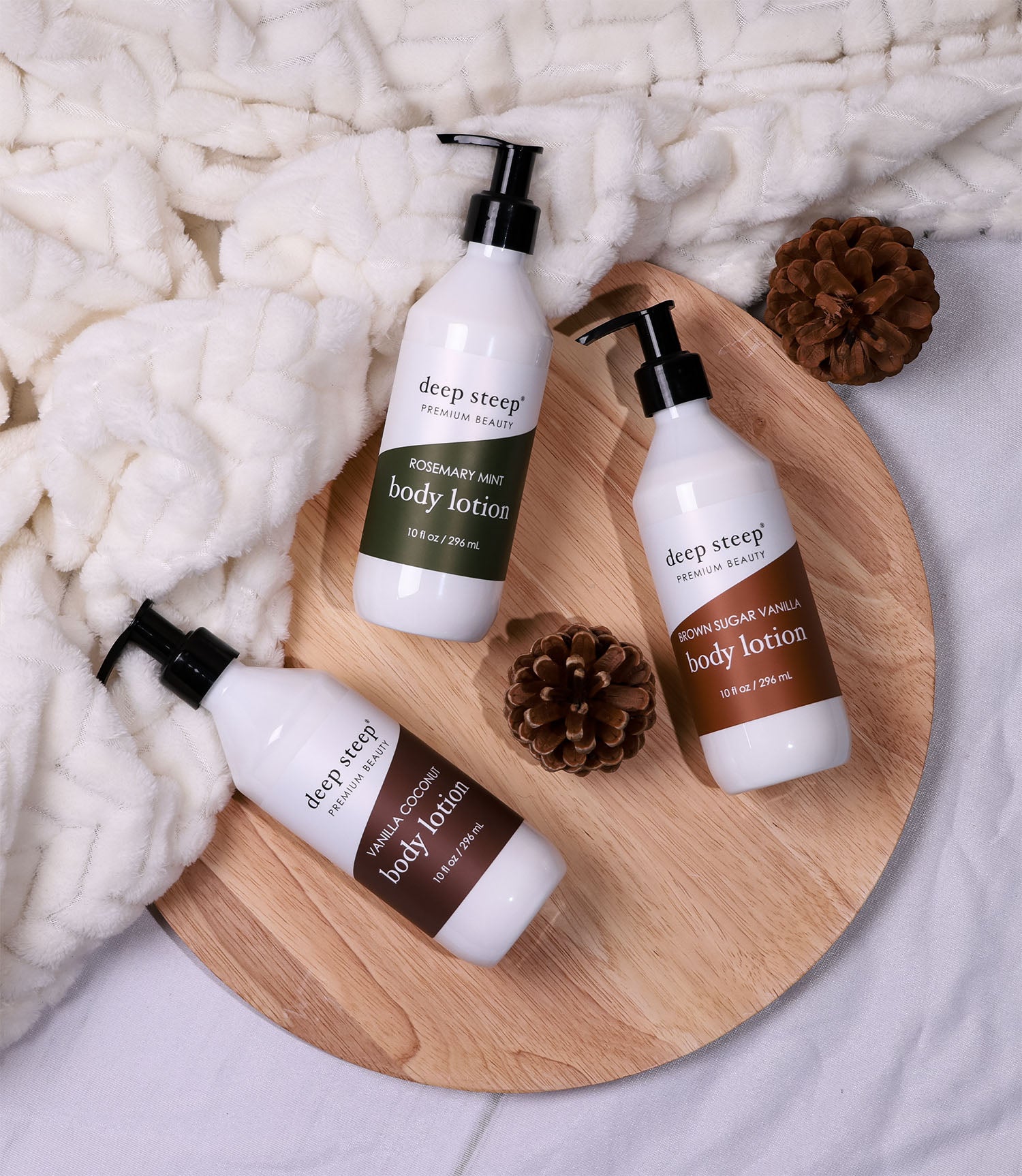 product photo of Deep Steep's body lotions laid out on a wooden board with a blanket and acorns