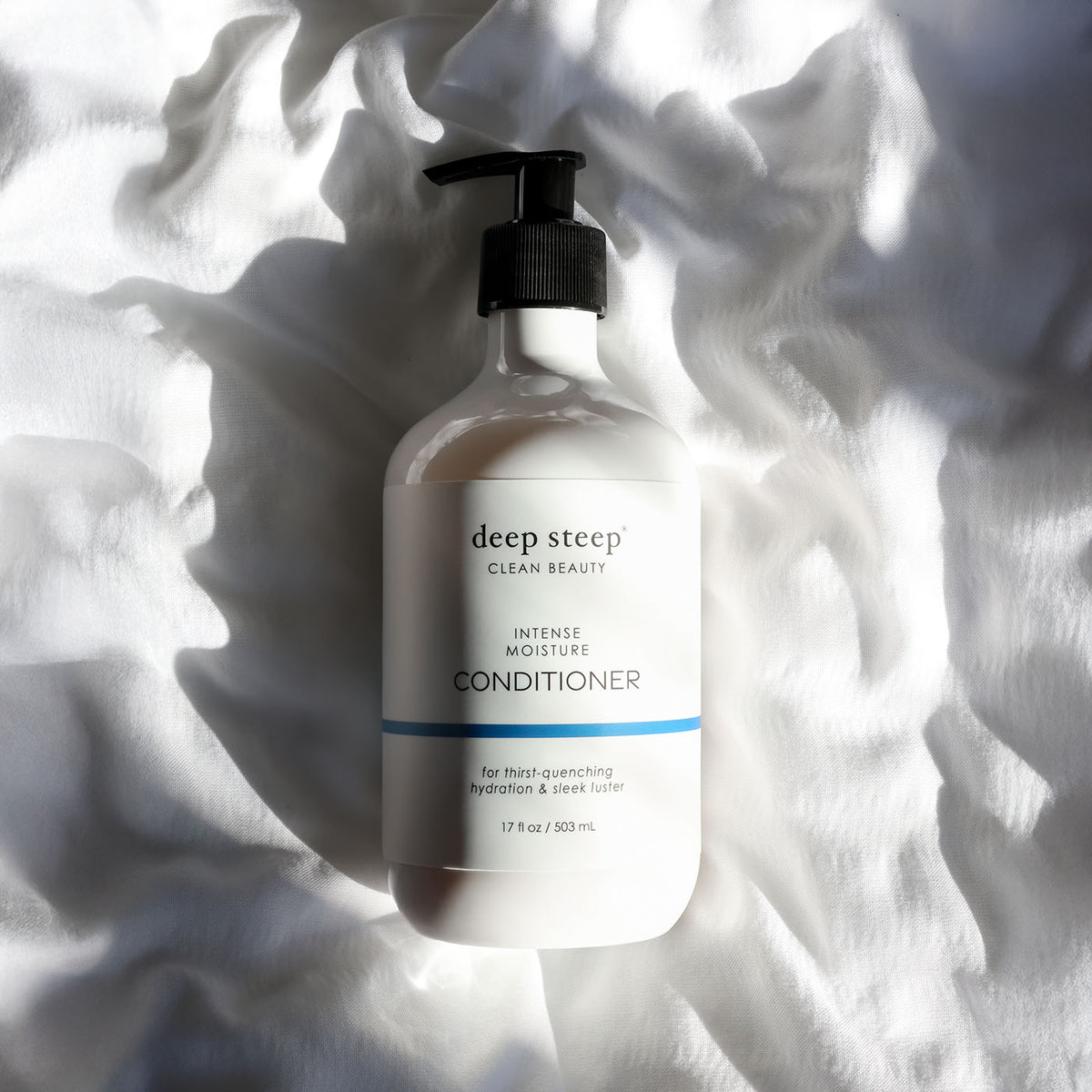 Bottle of Deep Steep Intense Moisture Conditioner on a textured white fabric background