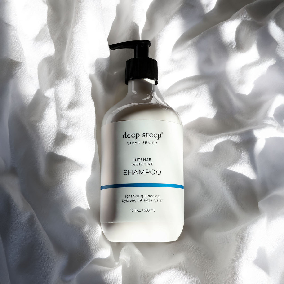 Bottle of Deep Steep Intense Moisture Shampoo on a textured white fabric background