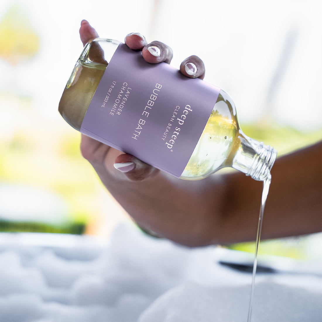 17 oz / 503 ml Deep Steep Lavender Chamomile bubble bath being poured from a bottle with a purple label
