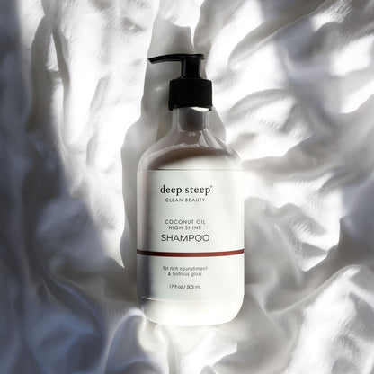 Bottle of Deep Steep Coconut Oil High Shine Shampoo on a textured white fabric background