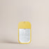 Front view of the Deep Steep Grapefruit & Bergamot Hydrating Mist pocket sanitizer spray in a bright yellow rectangular bottle with a clear front label against a solid beige background.
