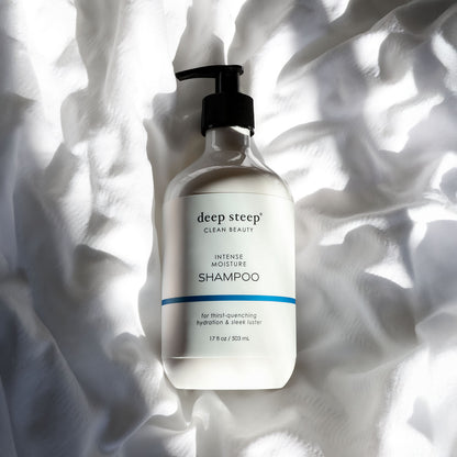 Bottle of Deep Steep Intense Moisture Shampoo on a textured white fabric background
