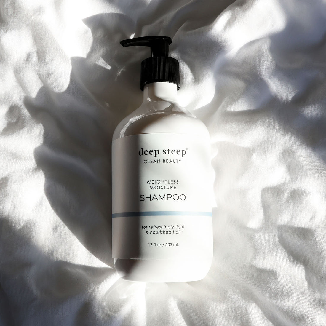 Bottle of Deep Steep Weightless Moisture Shampoo on a textured white fabric background